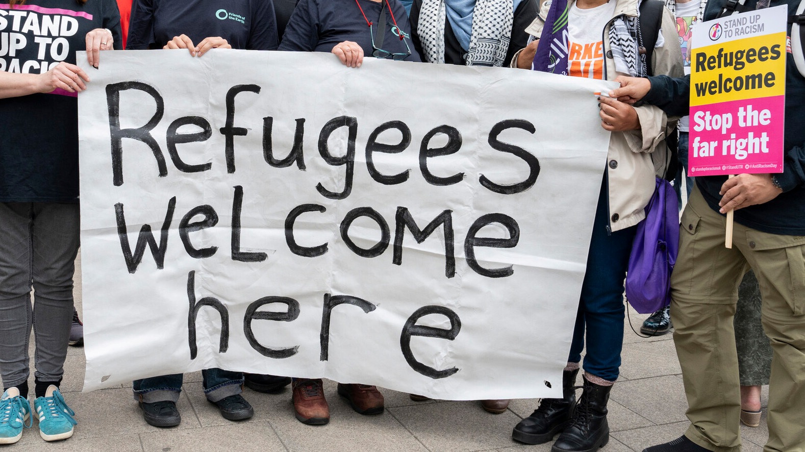 People holding up a banner saying "Refugees welcome here"