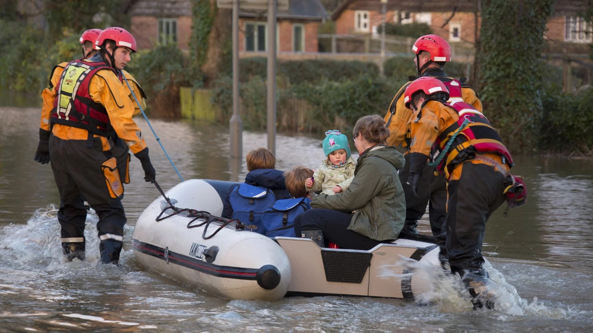 A family being rescued from floods in a rubber dinghy